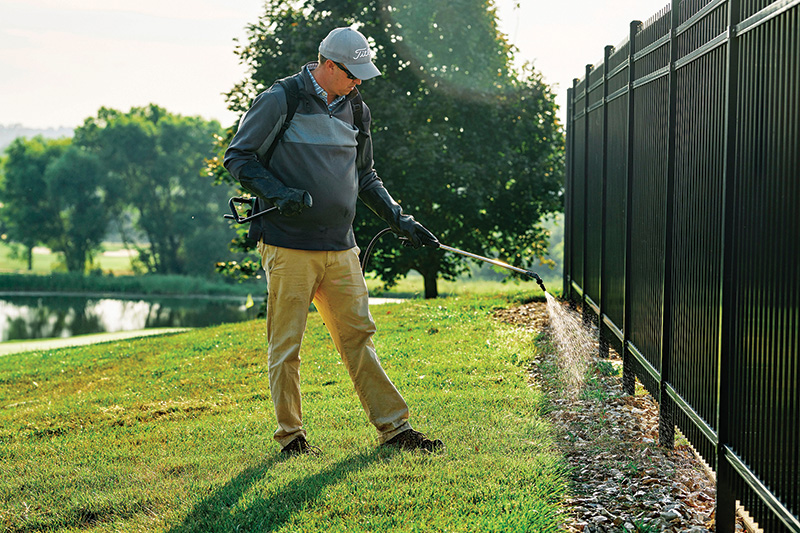 worker applying pesticides on a golf course
