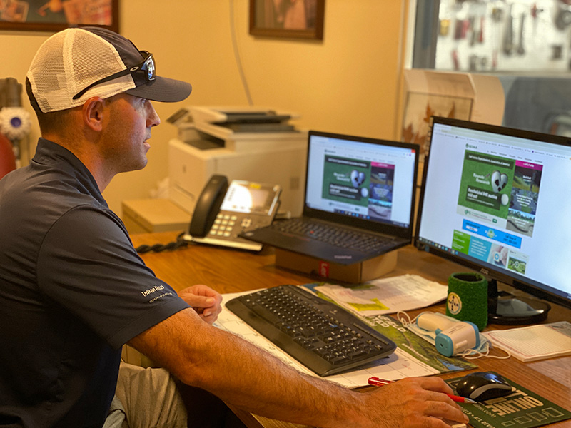 Man in white ballcap visiting the GCSAA web site in an office