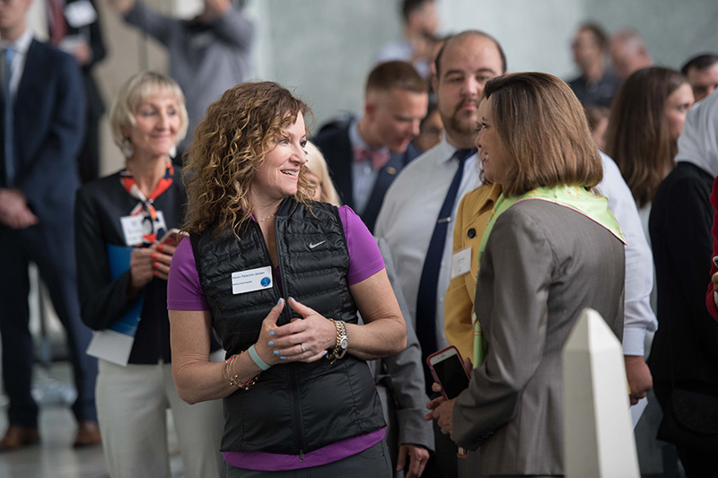 Two women speaking at a crowded event