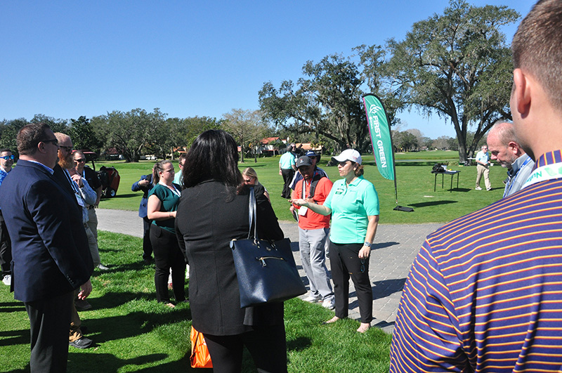 Leann Cooper outdoors on a golf course speaking to golf course superintendents