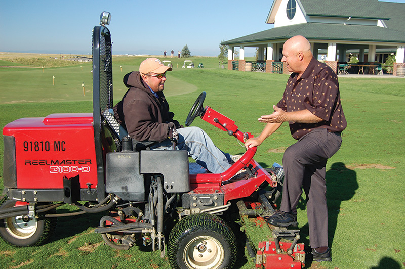 Dennis Lyon speaking with team member seated on a red tractor
