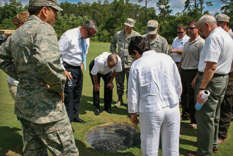 Eglin Air Force Base officials and agency officials examining fish at Eglin Golf Club