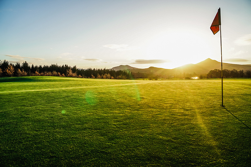 Golf course hole backlit by sunset