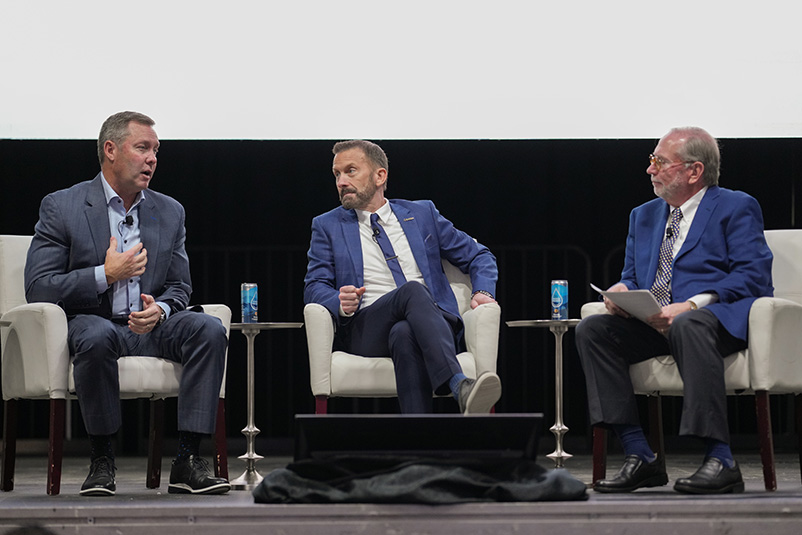 Three men sitting and talking on a stage