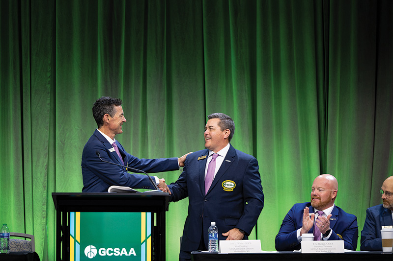 Two men shaking hands against a green background