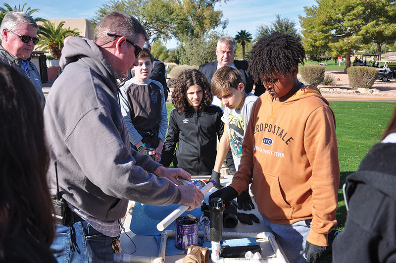 A man teaching a group of children in an outdoor setting
