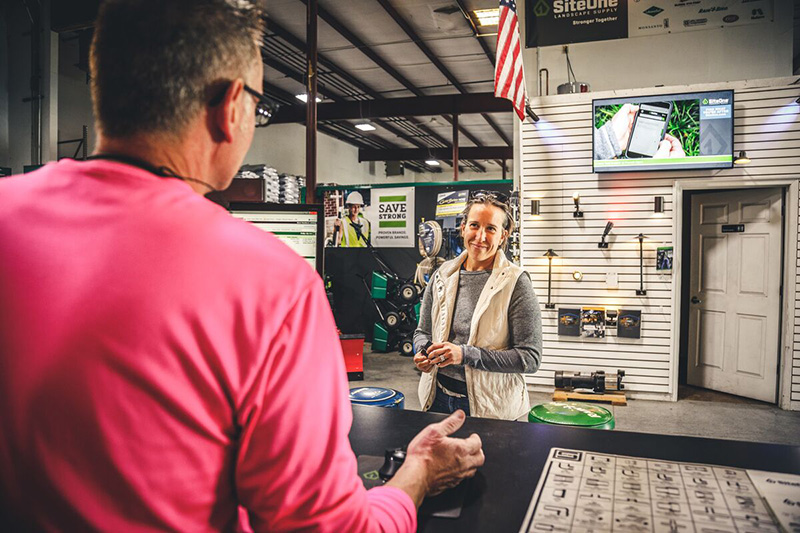 Woman speaking to man at counter about SiteOne and AOS products