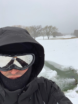 Man standing in snow on a golf course