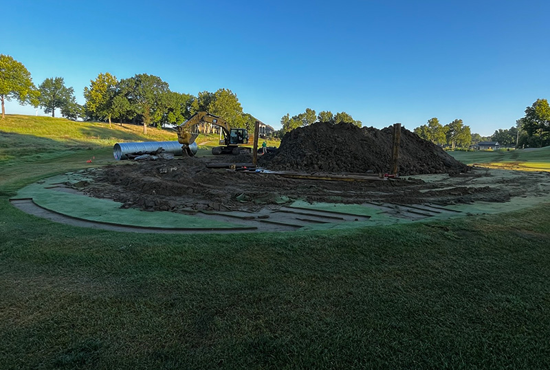 sinkhole repair in progress with construction vehicles and sod