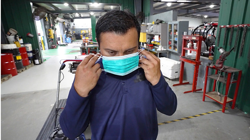 Person inside a golf course shop putting on a face mask to prevent germs