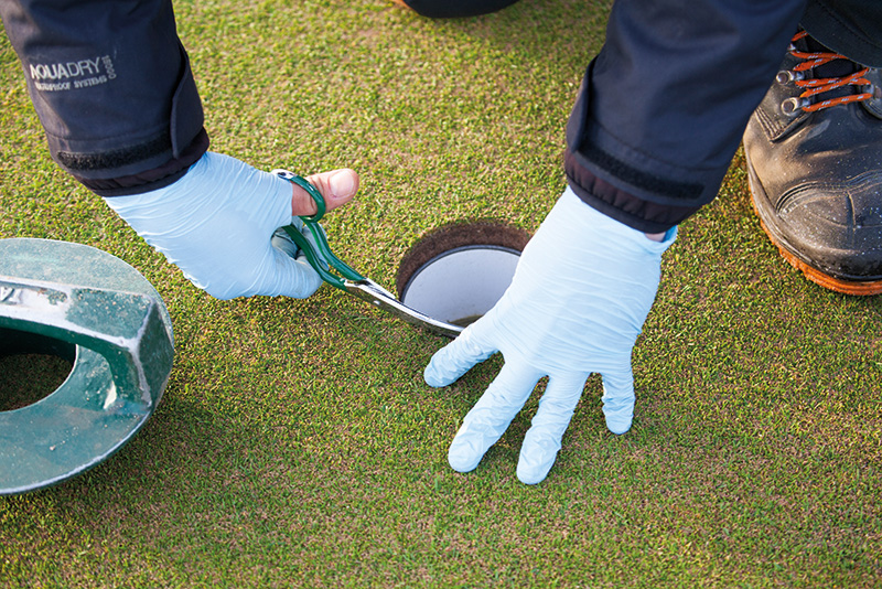 clipping grass near a hole at St. Andrews