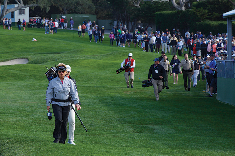 Dottie Pepper walking across a golf course with a camera crew