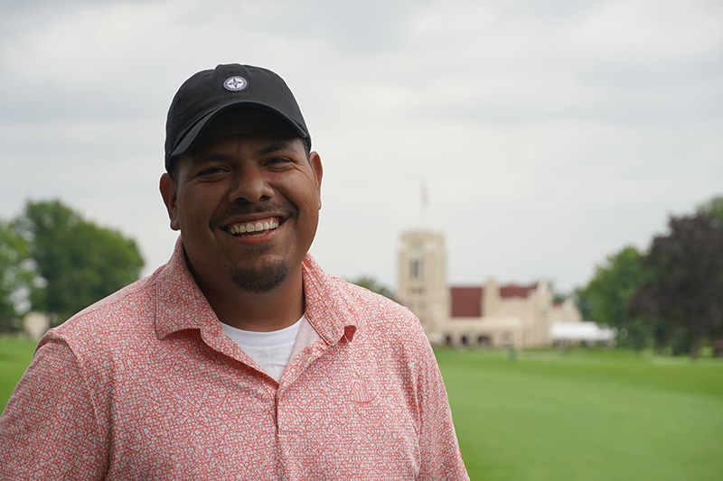 Francisco Velasquez standing outside, photographed from the shoulders up. He is wearing a pink polo and a black ball cap.