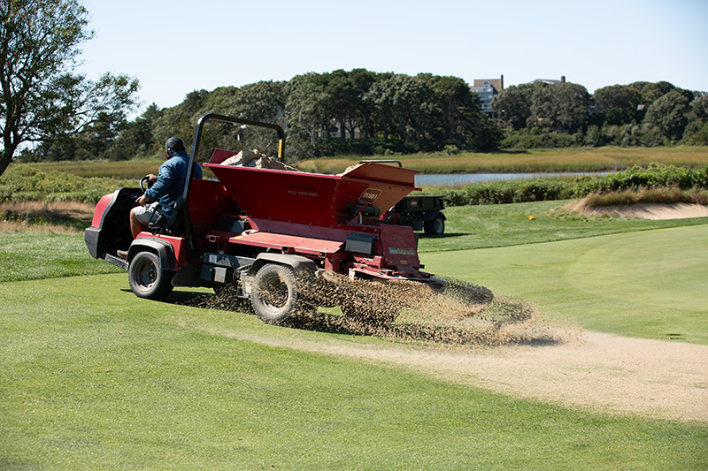 Spreading sand on a hole at Hyannisport club