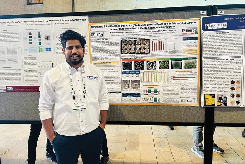 Mohammed Kyum standing in front of his research presentation board